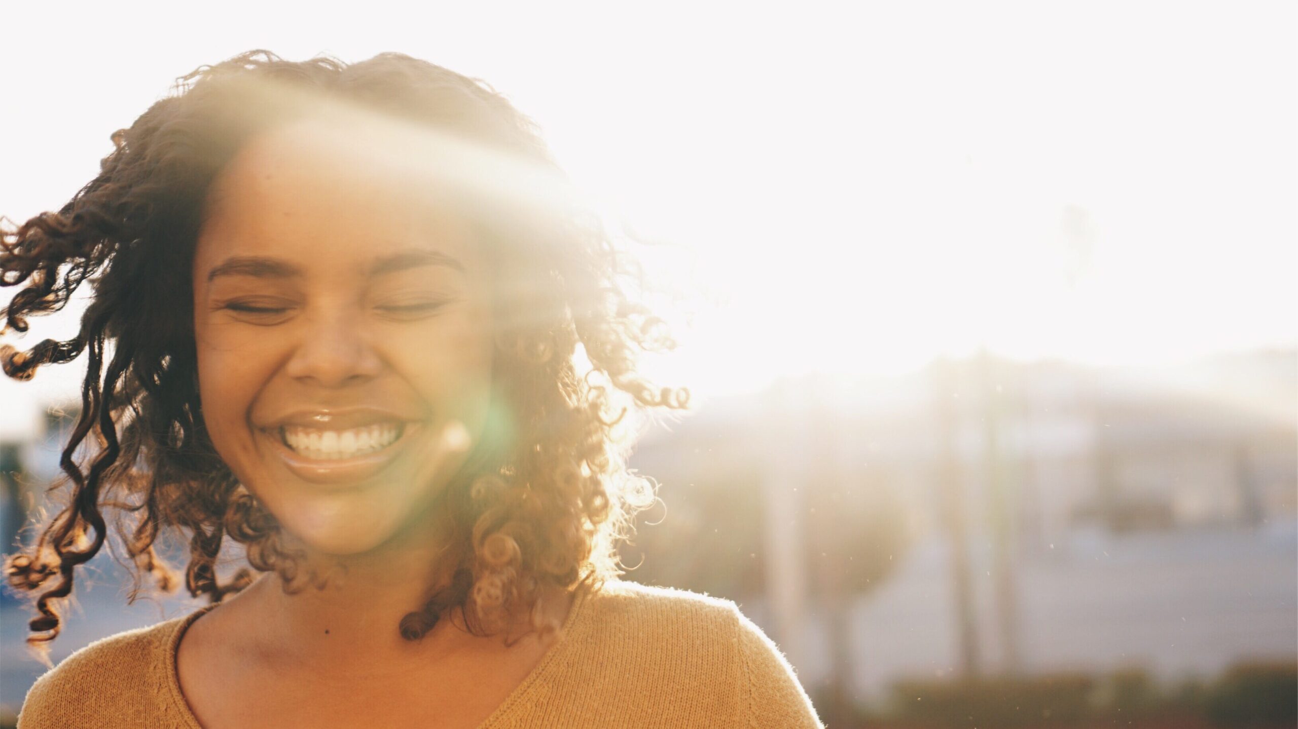 young woman with curly hair smiling with happiness 2022 11 15 21 04 44 utc edited scaled